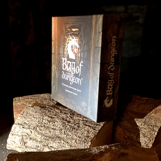Bag of Dungeon, dungeon crawler family board game by Gunpowder Studios, game box on top of logs