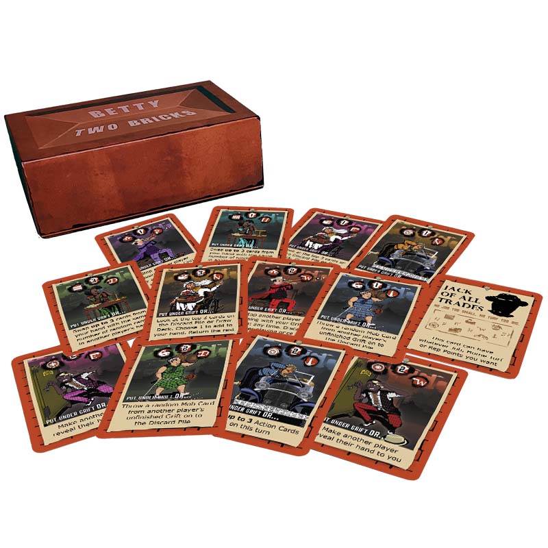 Some of the 45 Mob Cards from party card game Betty Two Bricks spread out in front of the game box that is shaped like a brick.