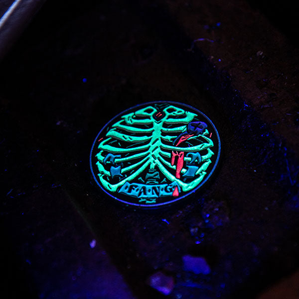 Image of Eat the Reich: F.A.N.G Challenge Coin glowing in the dark. This accessory for an RPG by Rowan, Rook & Decard is available at indie online boardgames and card games retailer Kaioss Games